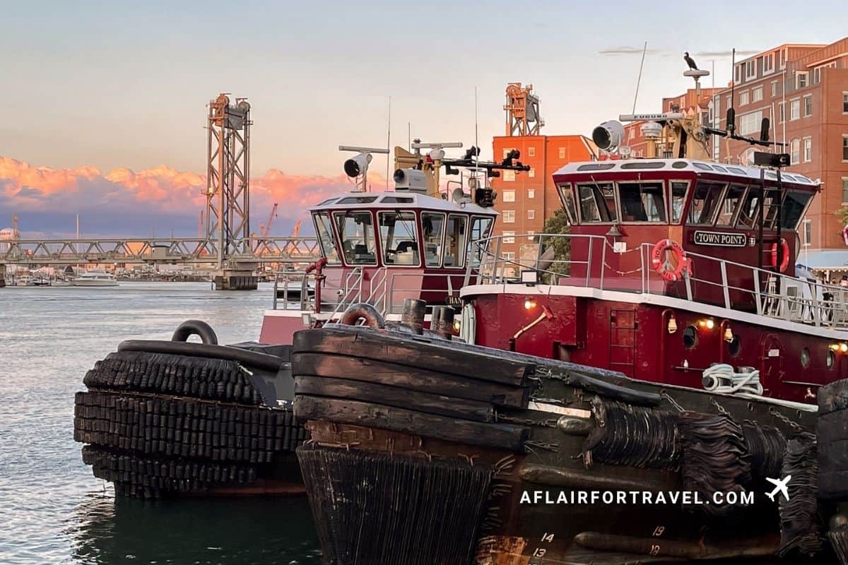 Red tugboats docked in Portsmouth Harbor at sunset with pink clouds overhead, New Hampshire in the fall