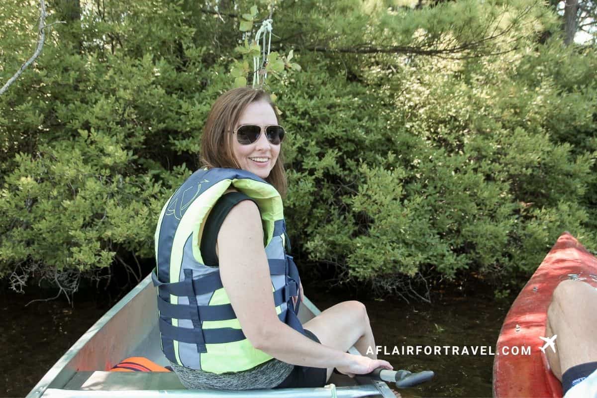 Traveler smiling from a canoe on a quiet, tree-lined New Hampshire pond