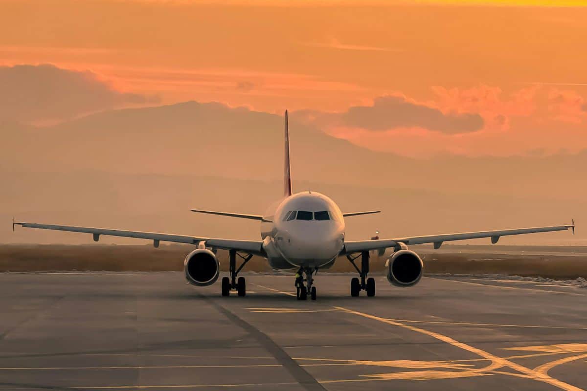 Commercial airplane sitting on a runway at sunset