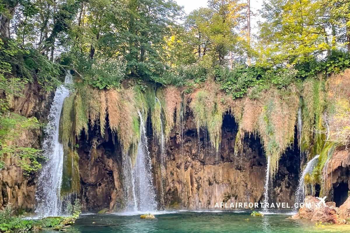 Moss-covered waterfalls flowing into a green pool at Plitvice Lakes