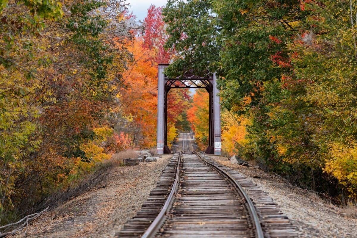 Historic railroad trestle bridge near North Conway framed by peak fall foliage in New Hampshire
