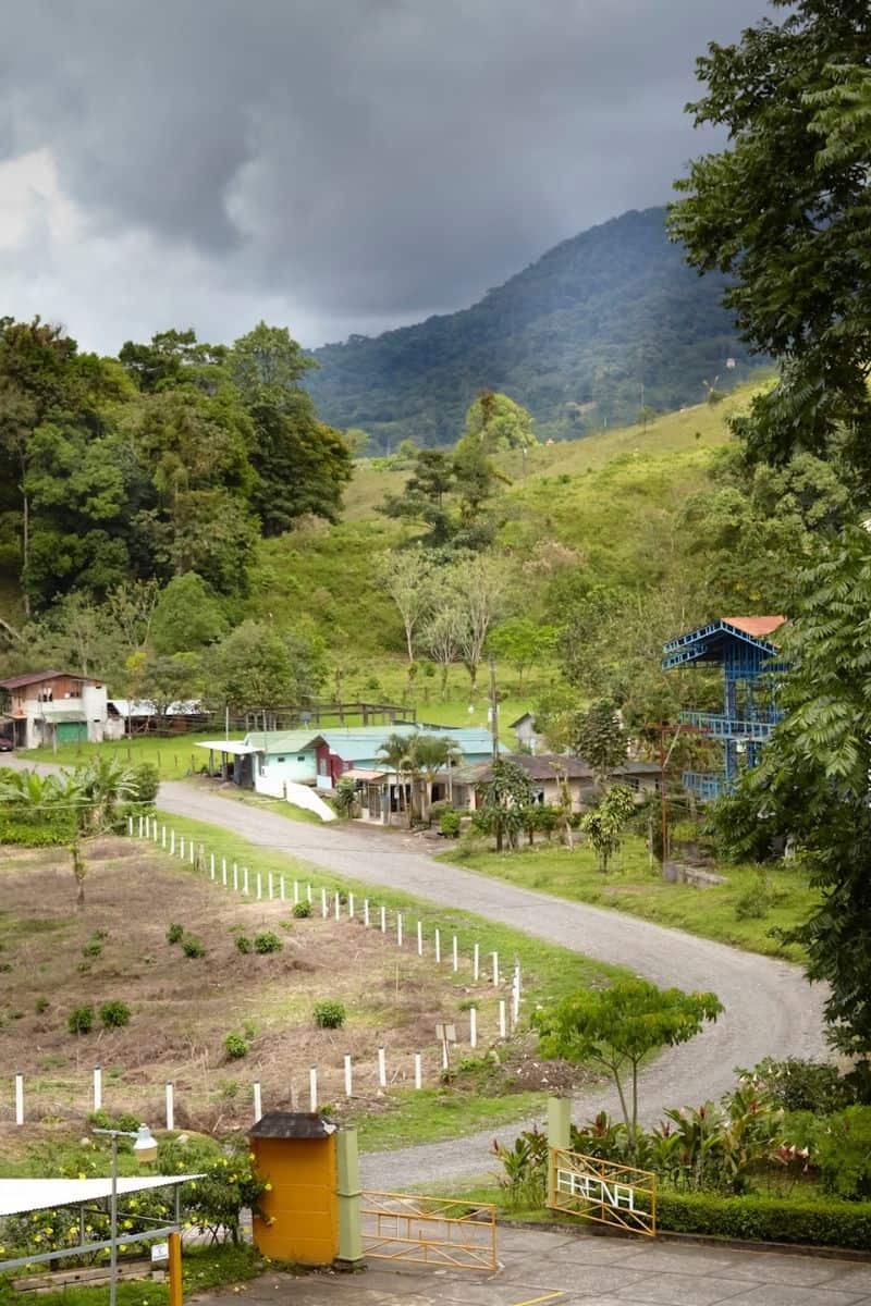 Hillside view of a rural Costa Rican village with a gravel driveway and mountain backdrop