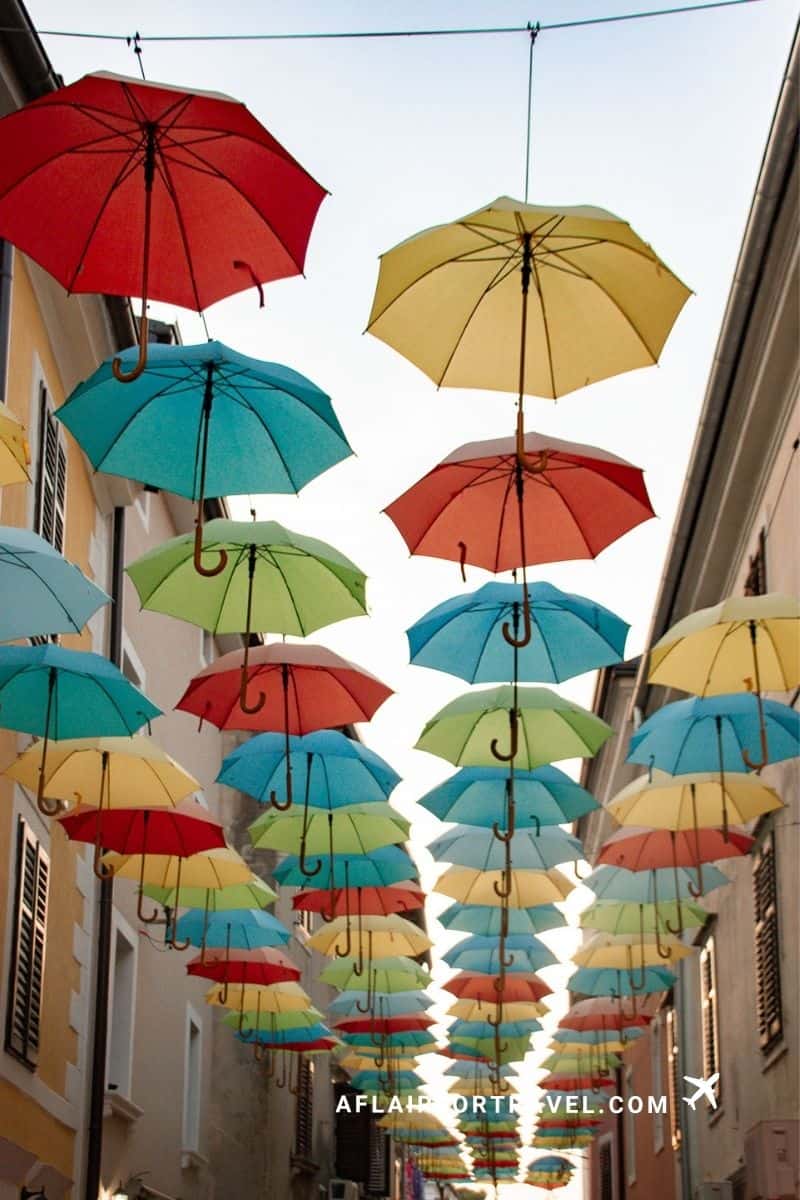 Colorful umbrellas hanging above a narrow street in the town of Novigrad in Istria, Croatia