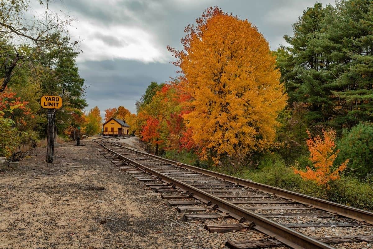 Railroad tracks passing a yard limit sign and vivid fall foliage in New Hampshire, a scenic spot for fall activities