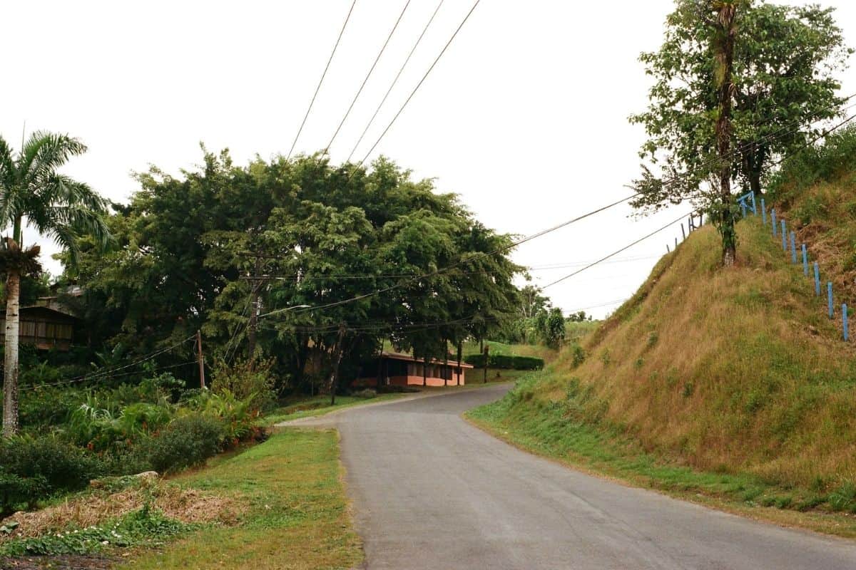 Paved road curving past a hillside home in the Costa Rican countryside