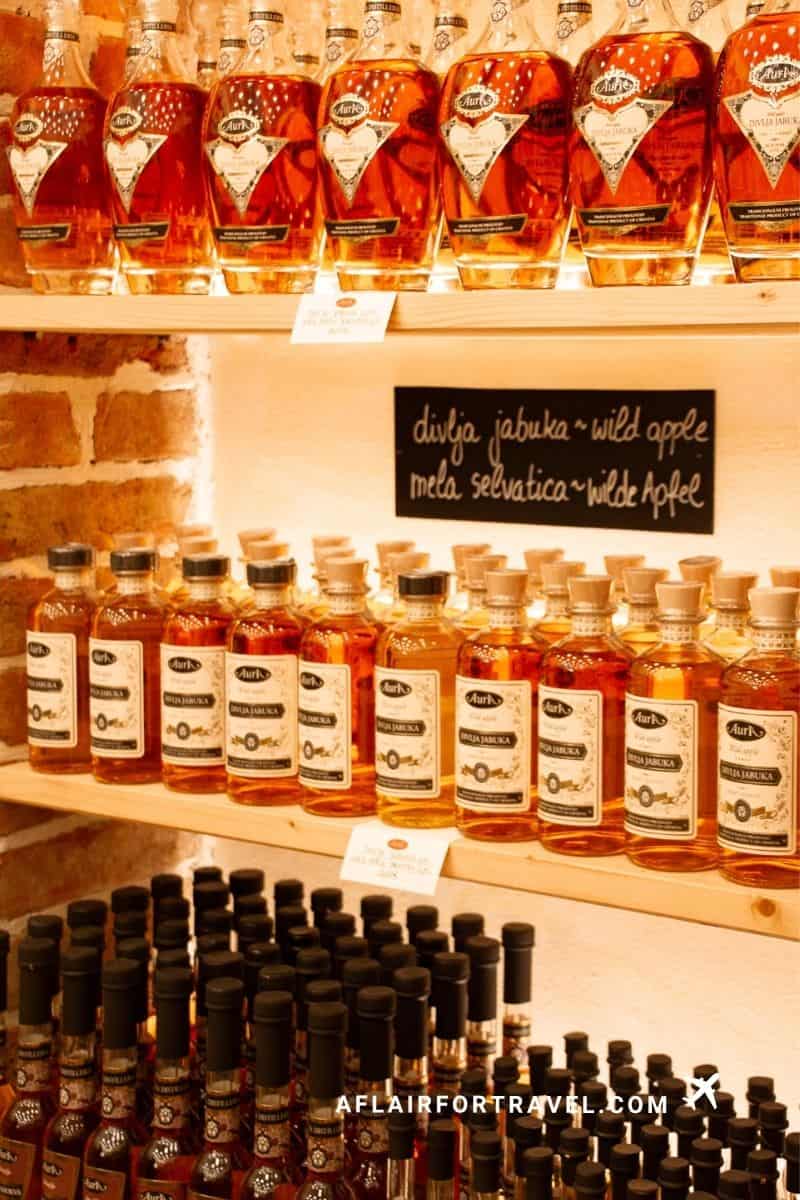Shelves of Croatian wild apple rakija at a local distillery shop, a fun souvenir stop for Croatia in September visitors