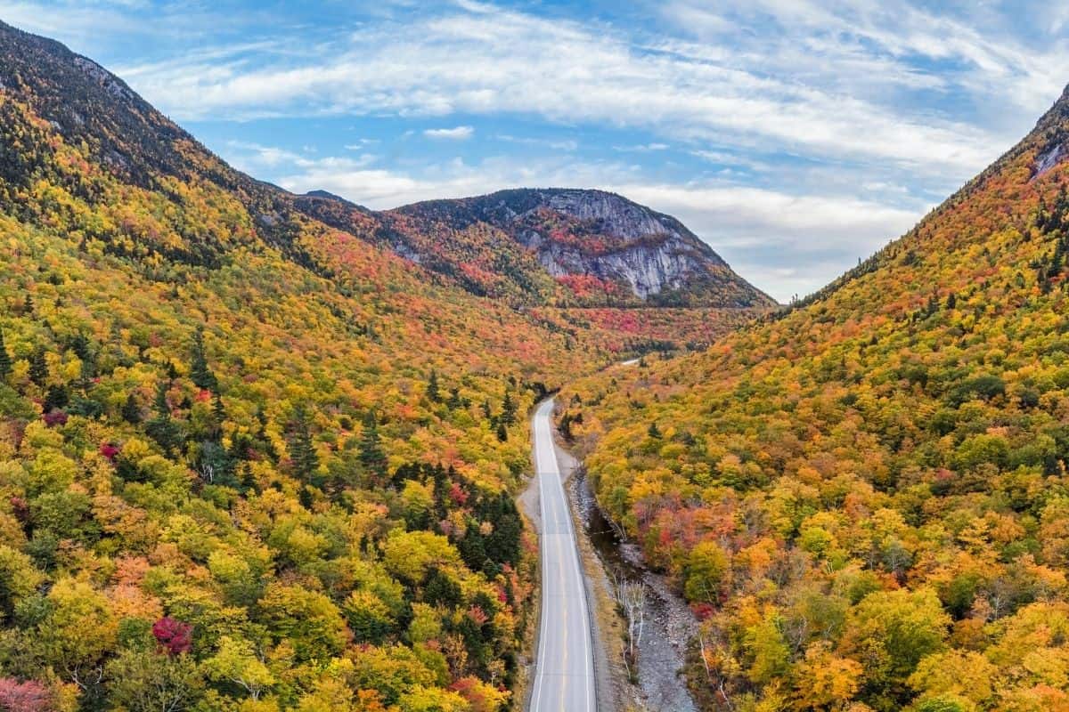 Aerial view of a road winding through Crawford Notch during fall foliage