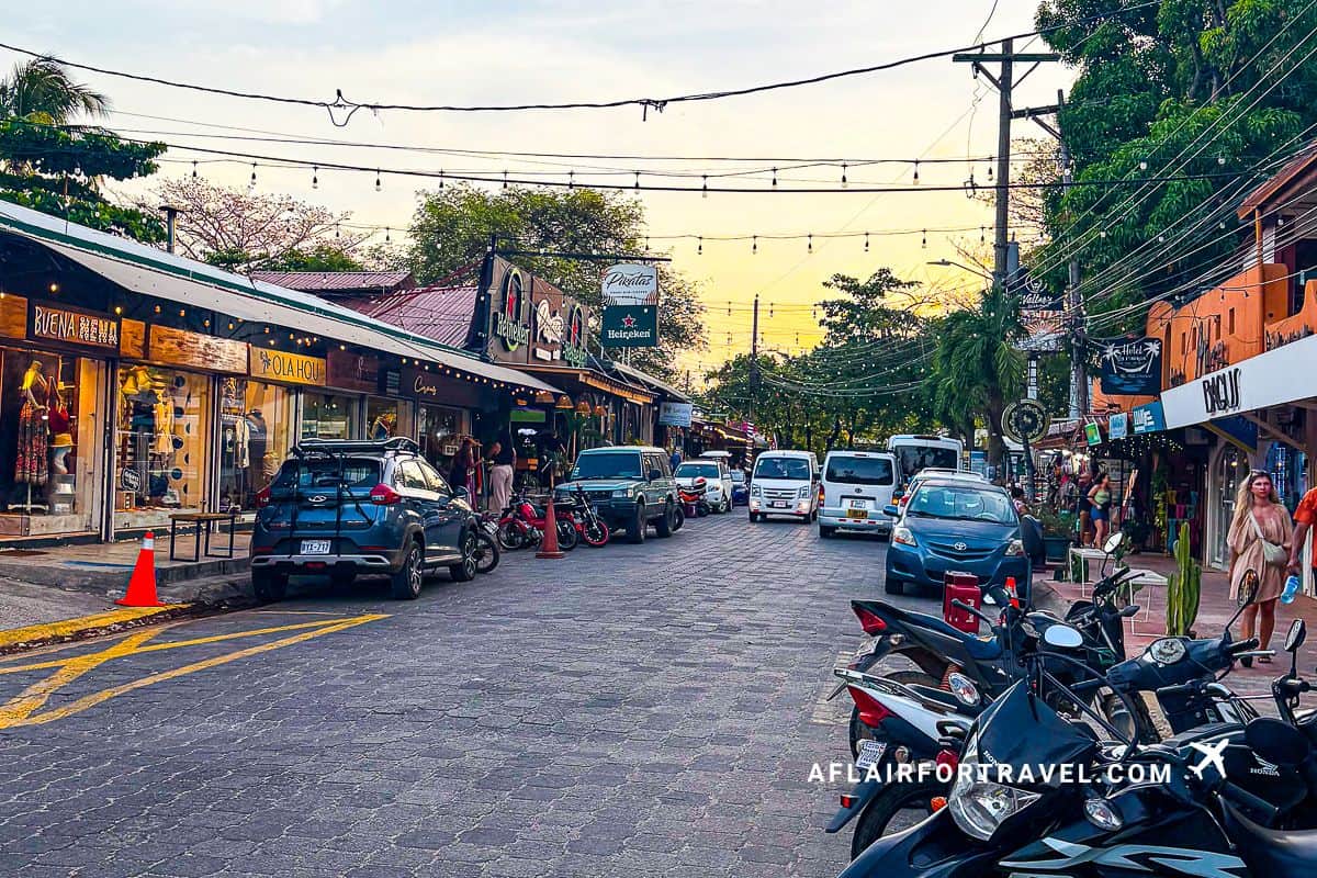 Sunset street scene with shops, cars, and motorbikes in a Costa Rican beach town