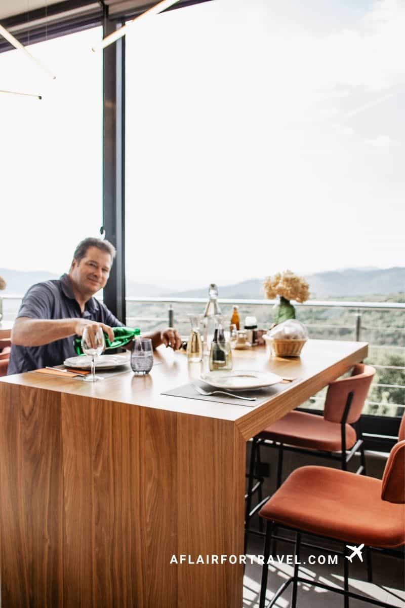 Man pouring sparkling water at a scenic hilltop restaurant table in Istria, Croatia