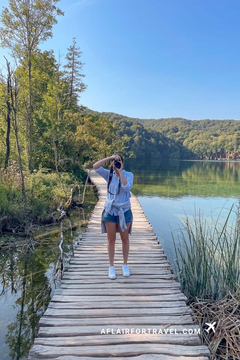 Woman photographing the lakes from a wooden boardwalk at Plitvice, a top stop for Croatia in September travelers