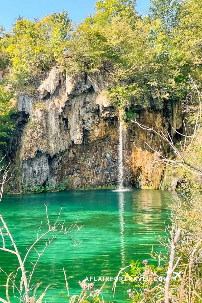 Waterfall pouring into an emerald-green lake at Plitvice Lakes National Park