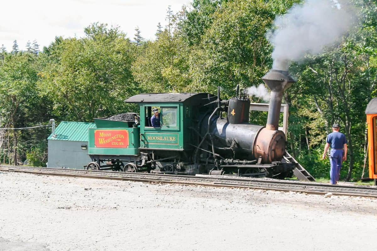 Mount Washington Cog Railway steam engine Moosilauke with conductor in the cab, smoke billowing from the stack.