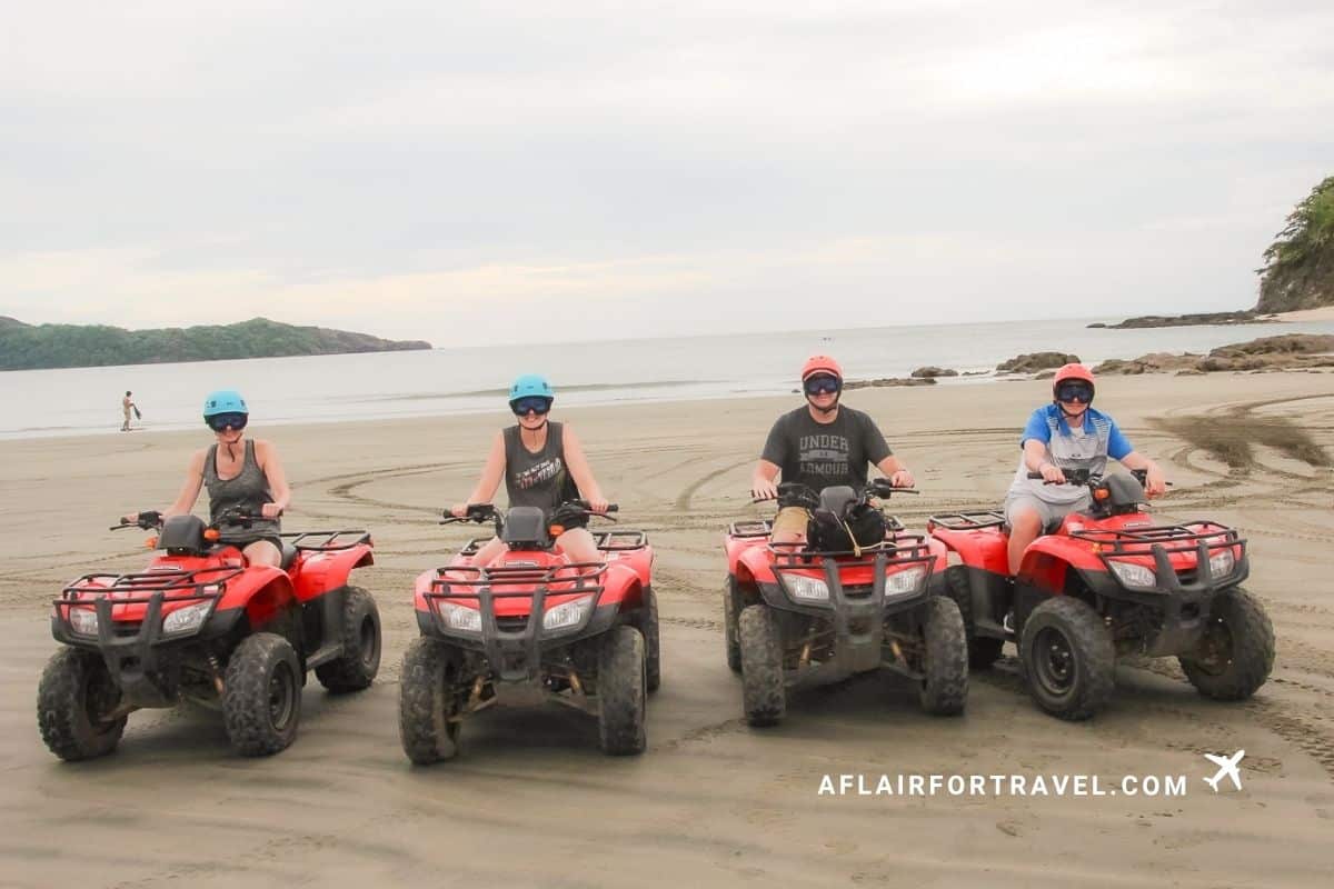 Family of four sitting on ATVs on a beach in Costa Rica