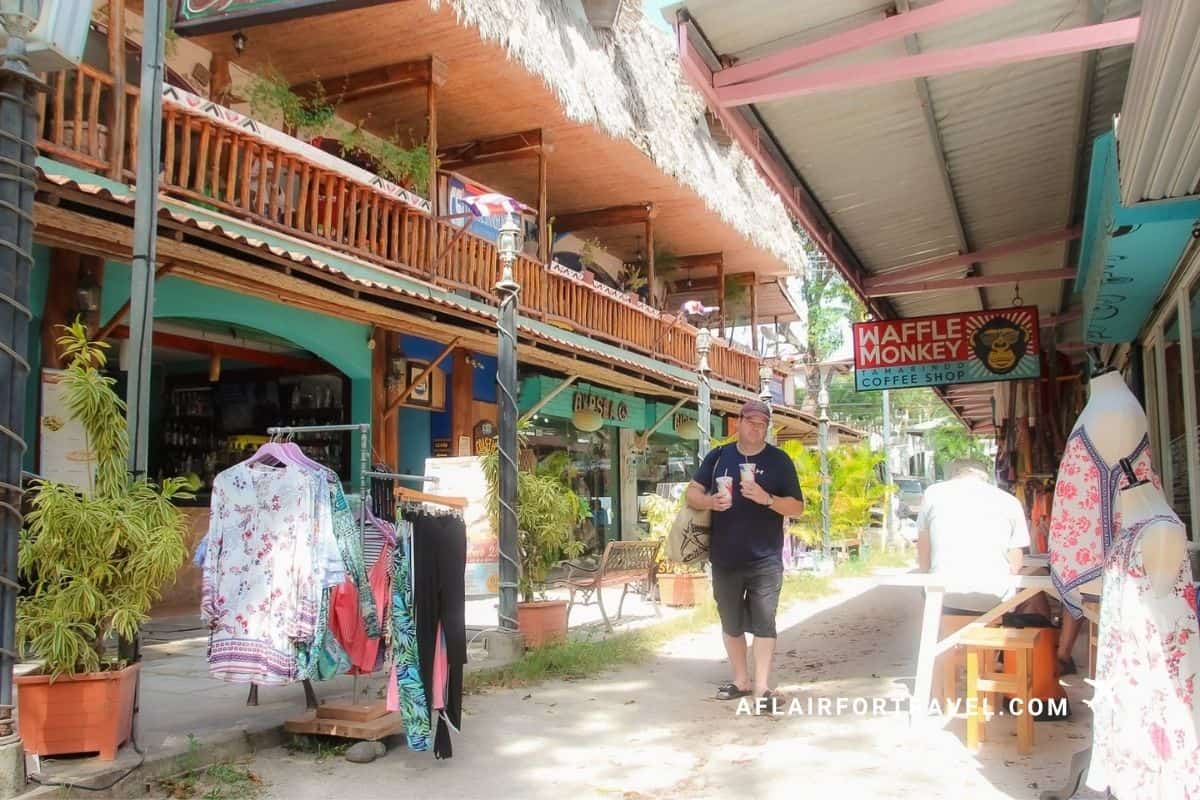Man walking past colorful shops and cafes along a side street in Tamarindo