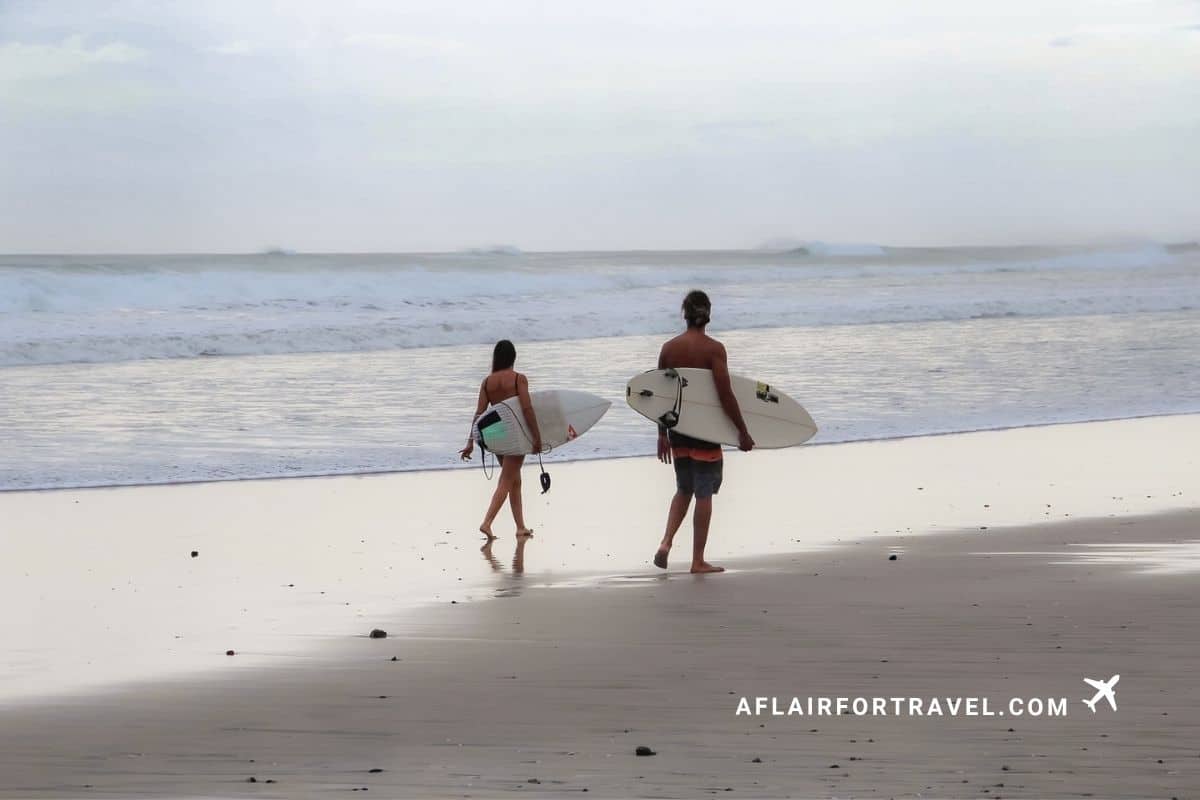 Surfers walking along the beach at dusk in Guanacaste, Costa Rica