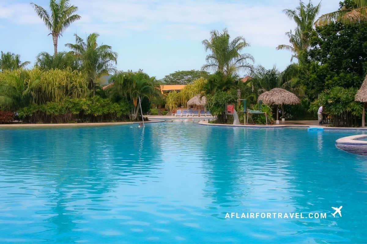 Quiet resort pool surrounded by palm trees; consider amenities when deciding if all-inclusive resorts in Guanacaste are worth it