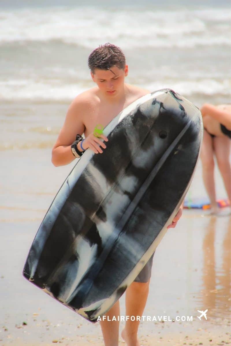 Teen carrying a bodyboard on the beach in Guanacaste, Costa Rica