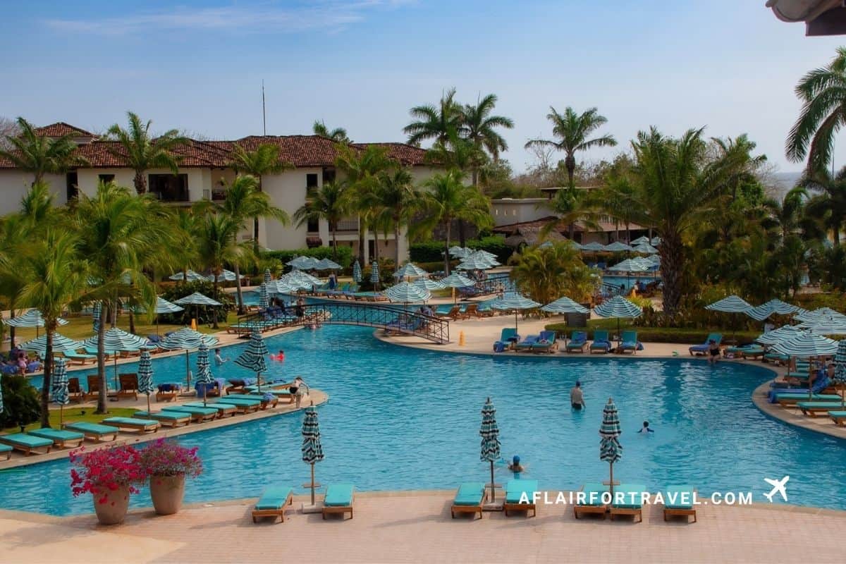 Resort pool lined with striped umbrellas and lounge chairs at a Guanacaste, Costa Rica resort