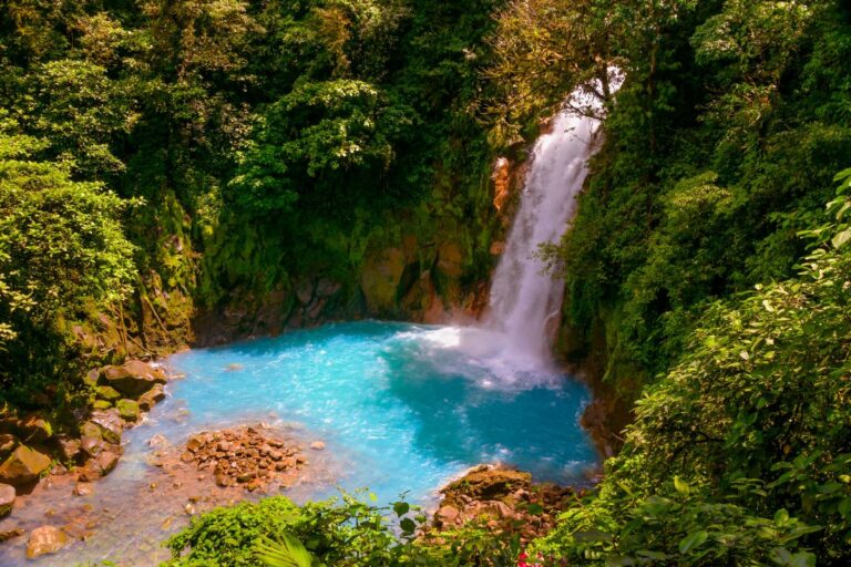 La Fortuna turquoise waterfall cascading into a clear blue pool surrounded by lush green rainforest
