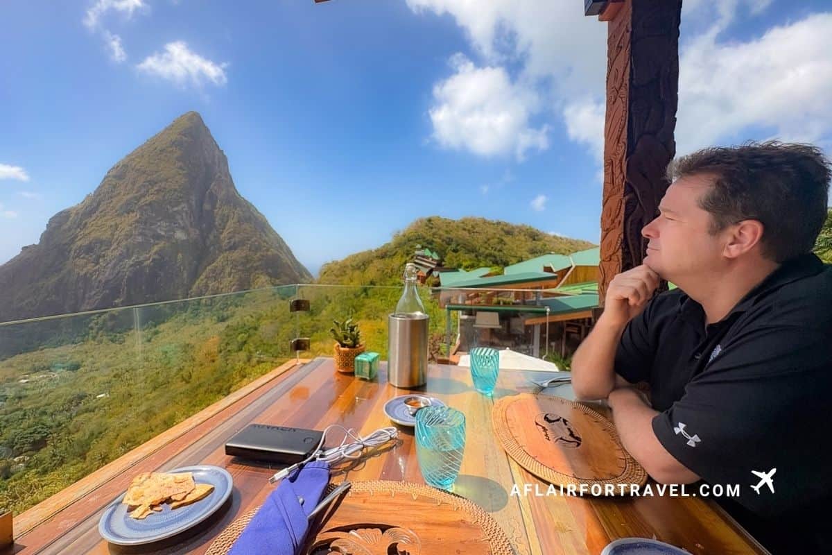 Man enjoying a meal with a view of Petit Piton from a cliffside restaurant, St. Lucia