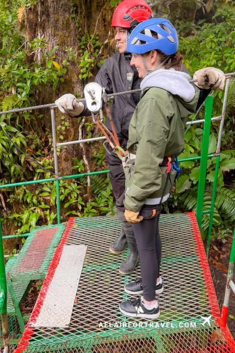 Two people in helmets and harnesses on a zipline platform in the cloud forest, an adventure day to factor into how many days you need in Costa Rica